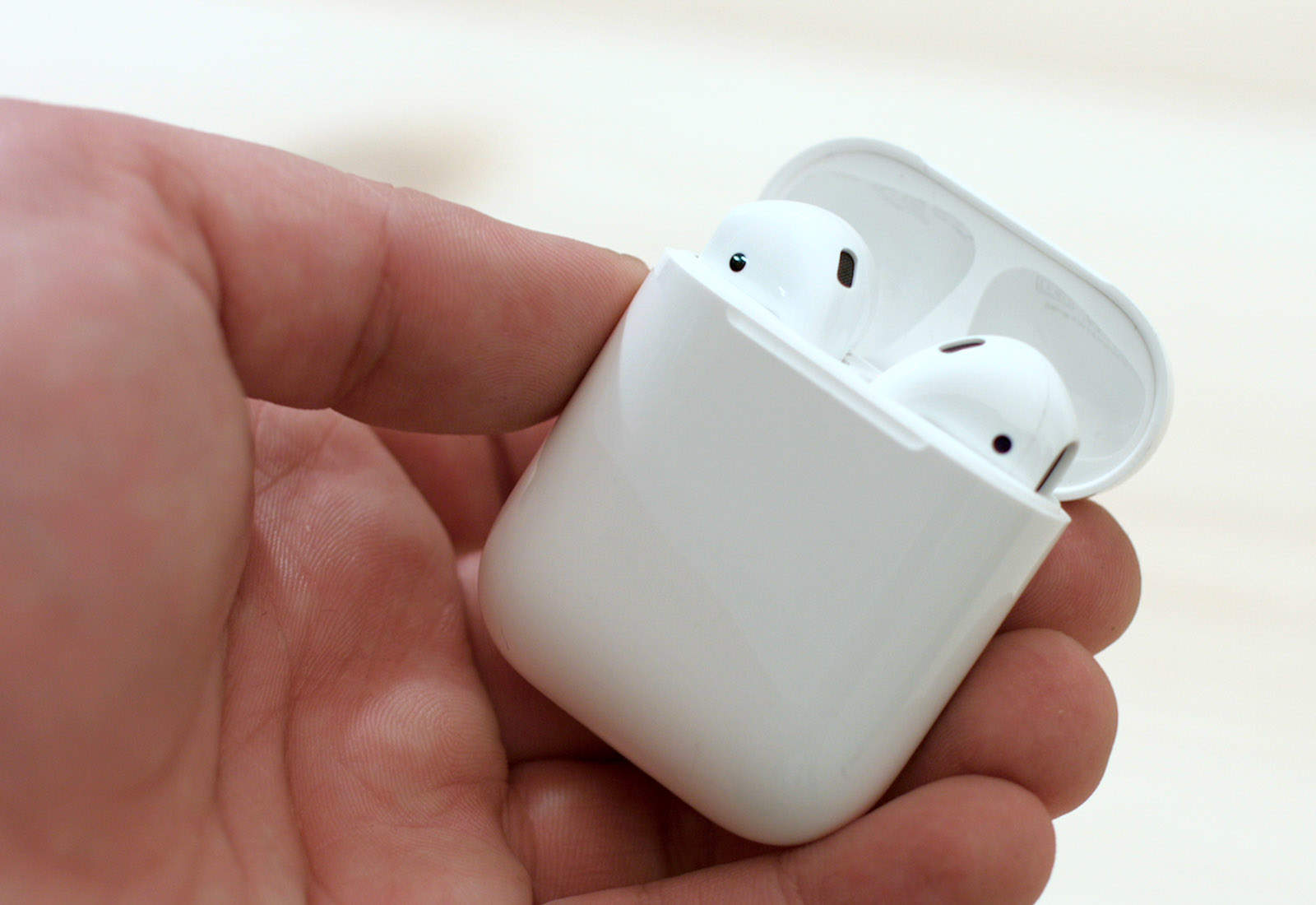 A hand holding a pair of AirPods