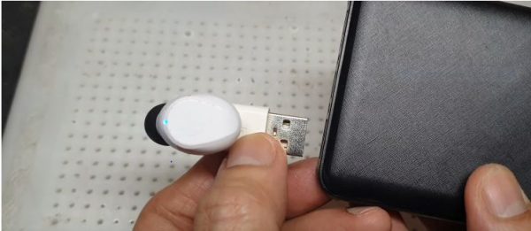 A person carefully inserting the USB adapter (or modified cable) into the USB port of a phone.