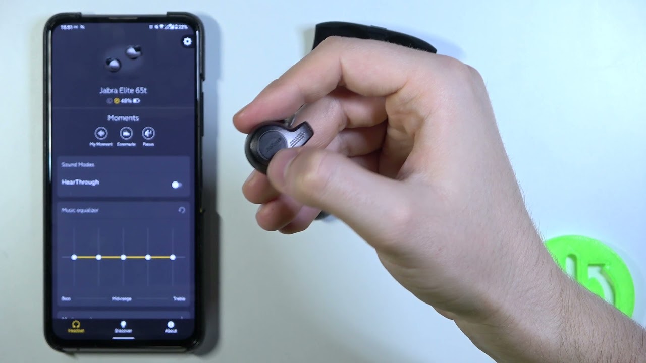 A person resetting the Earbuds while jabra elite 65t app is opened on a cell phone in the background
