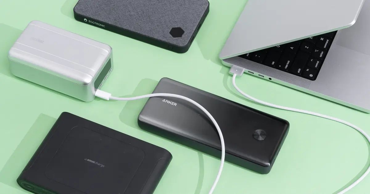 4 power banks placed along side a laptop while one of these power banks is connected to the laptop through a cable