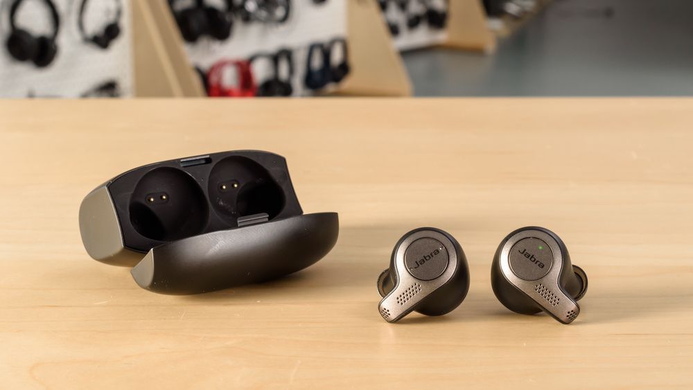 jabra elite 65t earbuds places on a wooden table along with the case 