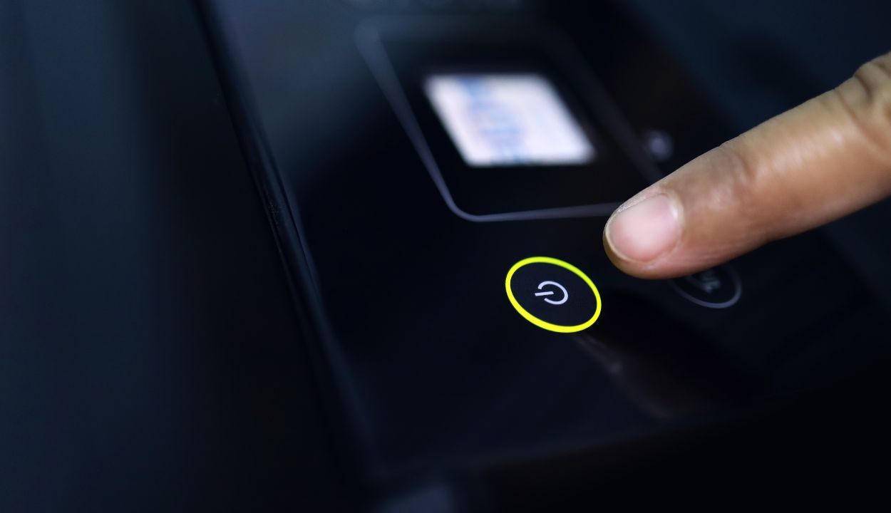 Highlighted power button of TCL TV that a male hand is pressing 